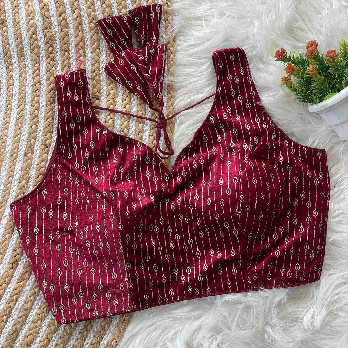Red patterned top on a textured surface with a small plant in the corner