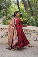 Woman in a red traditional outfit with a patterned shawl standing outdoors.