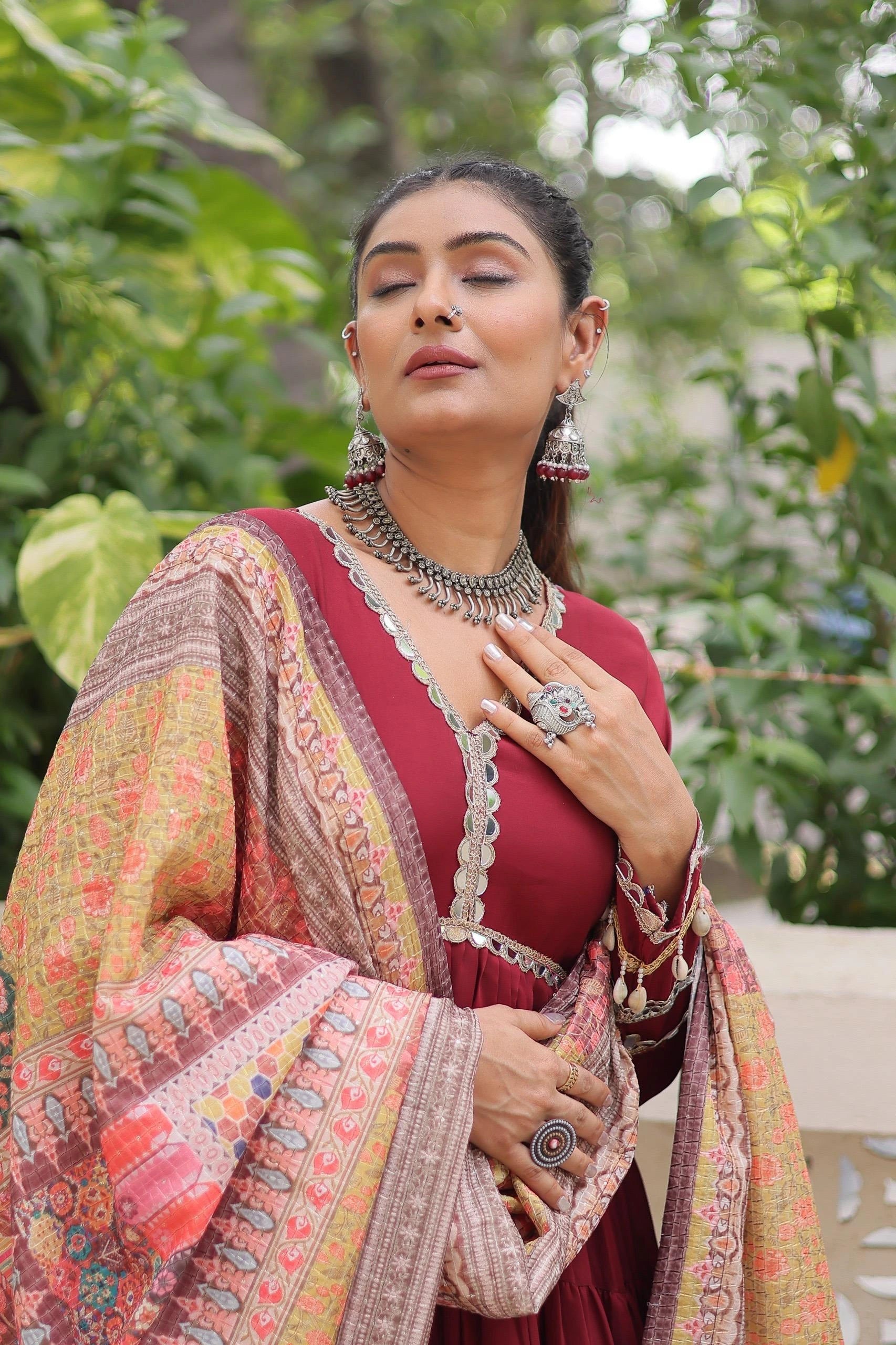 Woman in traditional attire with jewelry against a natural background