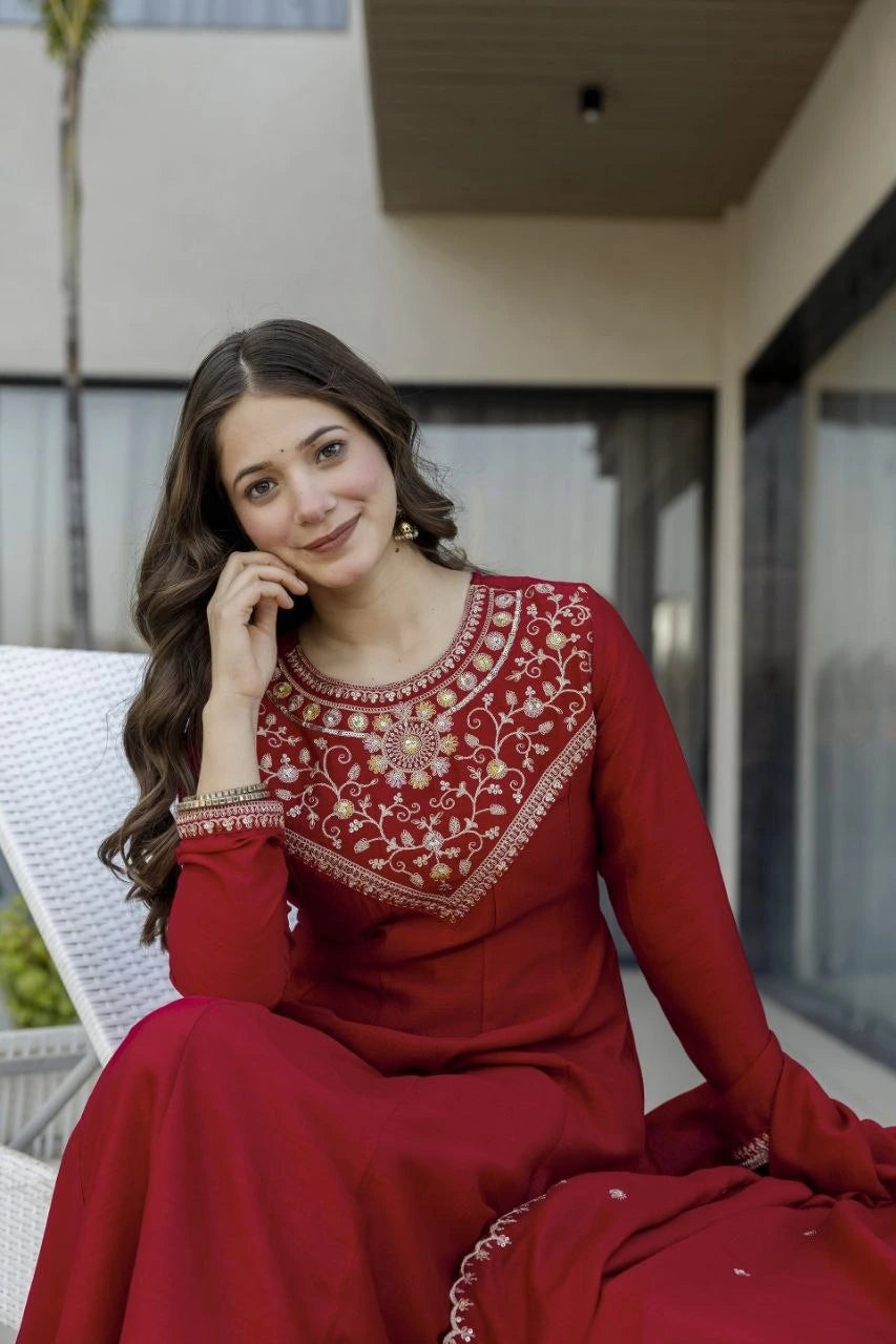 Woman in a red traditional outfit sitting outdoors.