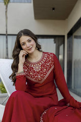 Woman in a red traditional outfit sitting outdoors.