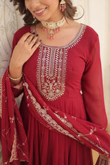 Red embroidered traditional outfit with jewelry on a neutral background