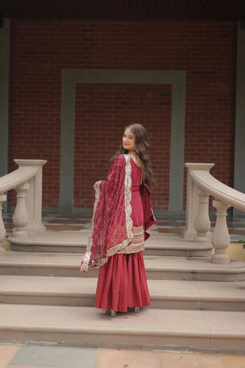 Woman in a red traditional outfit standing on steps with a brick wall background