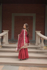 Woman in a red traditional outfit standing on steps with a brick wall background