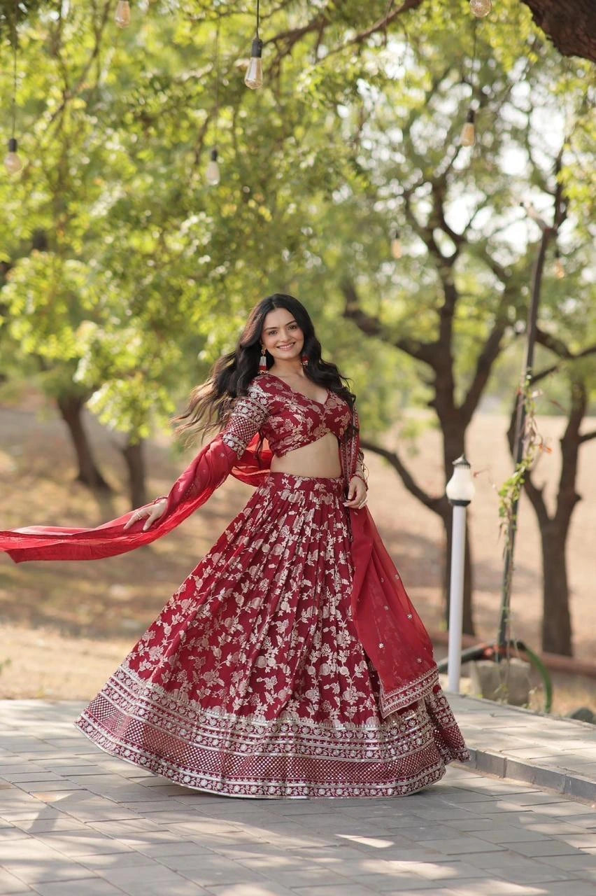 Woman in a red and white traditional outfit standing outdoors with trees in the background