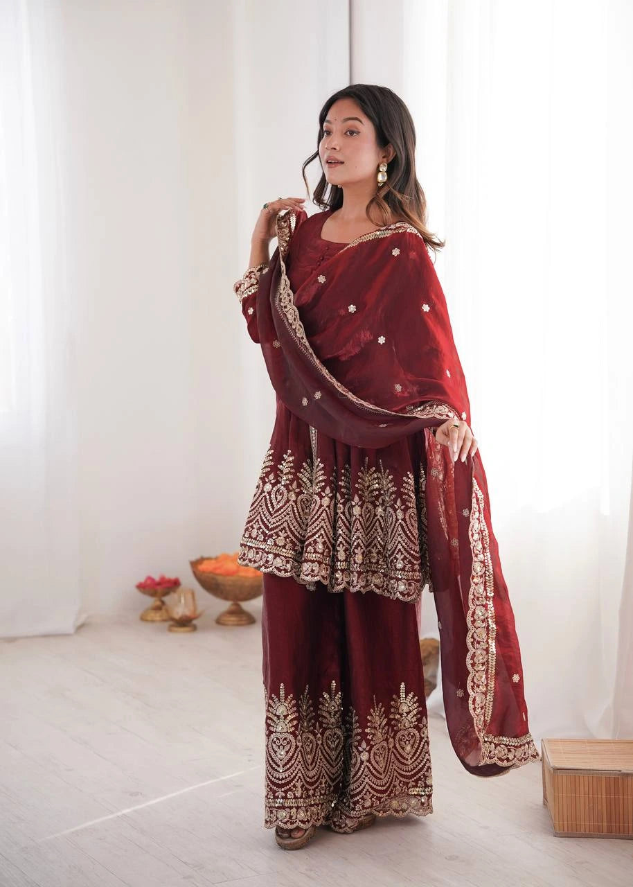 Woman in a maroon traditional outfit with gold patterns in a minimalistic setting