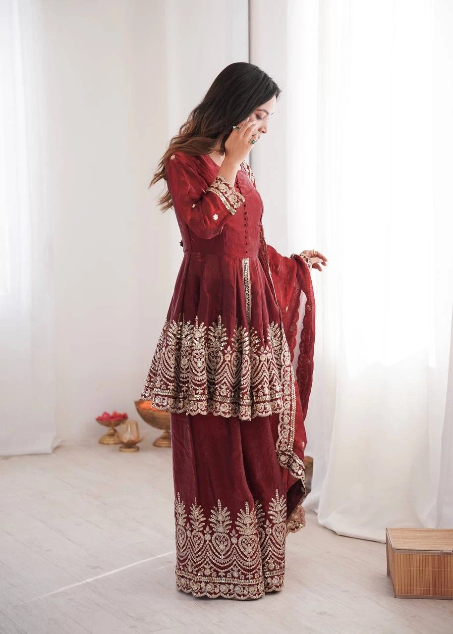 Woman wearing a red traditional outfit with white patterns in a minimalistic setting