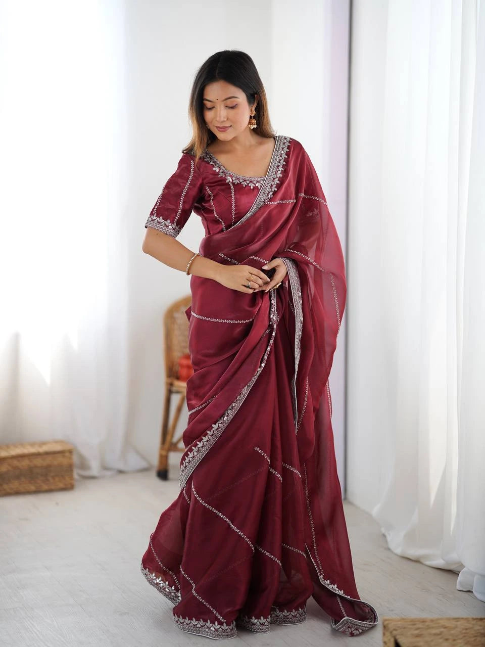 Woman wearing a maroon saree with white patterns in a minimalistic setting