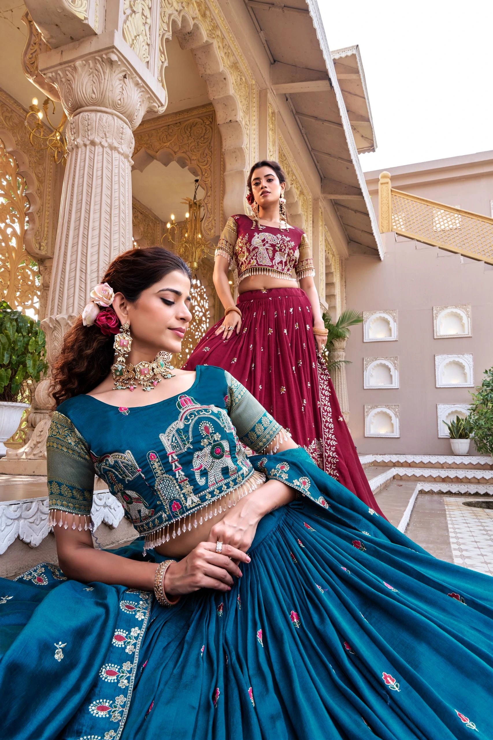 Two women in traditional outfits standing in an architectural setting.