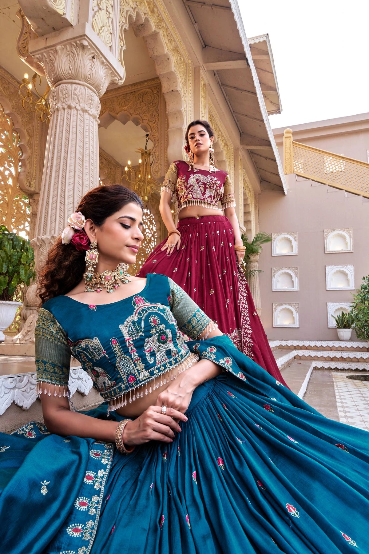 Two women in traditional outfits standing in an architectural setting.