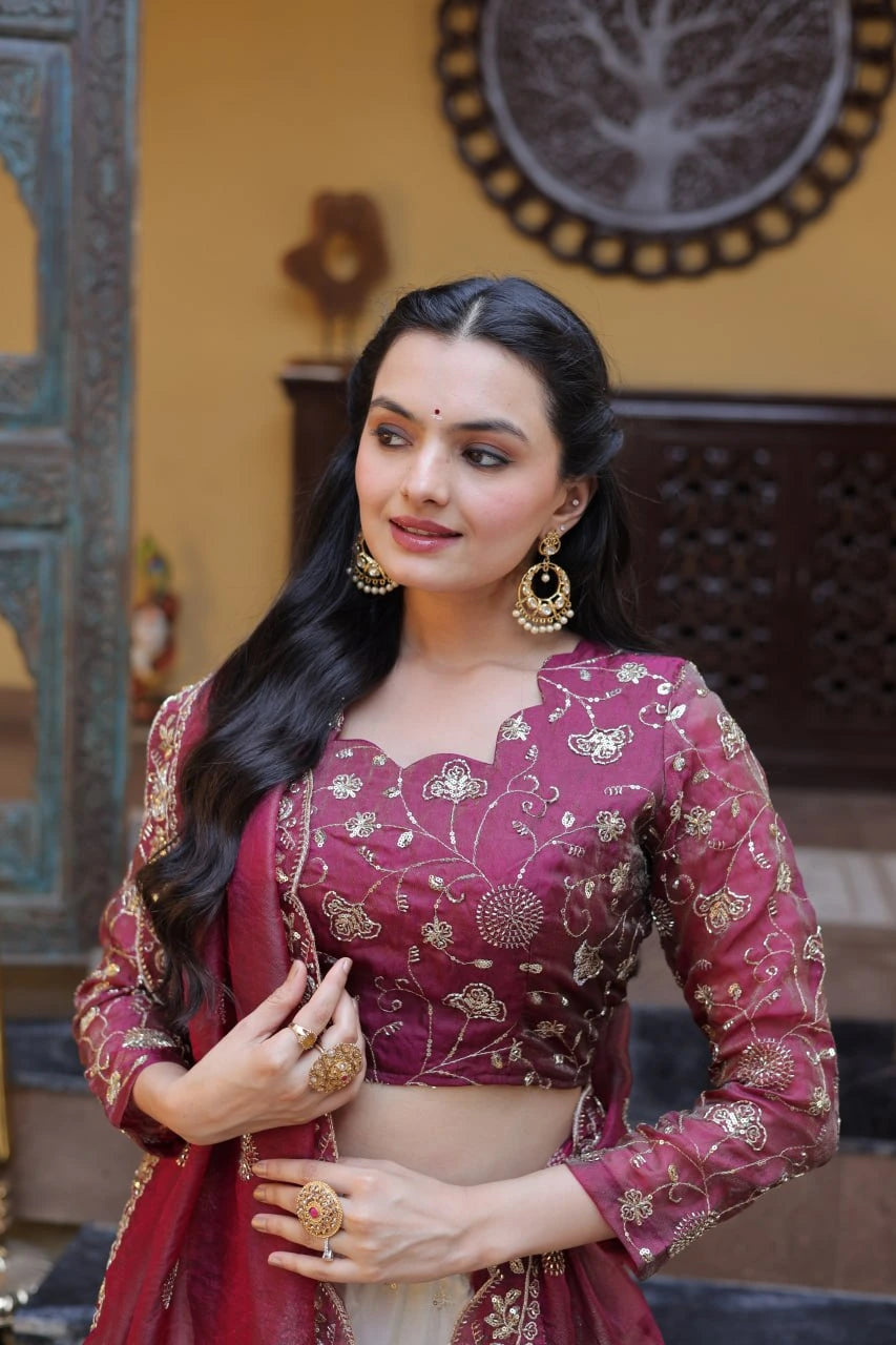 Woman in a traditional pink and red saree with gold patterns indoors.