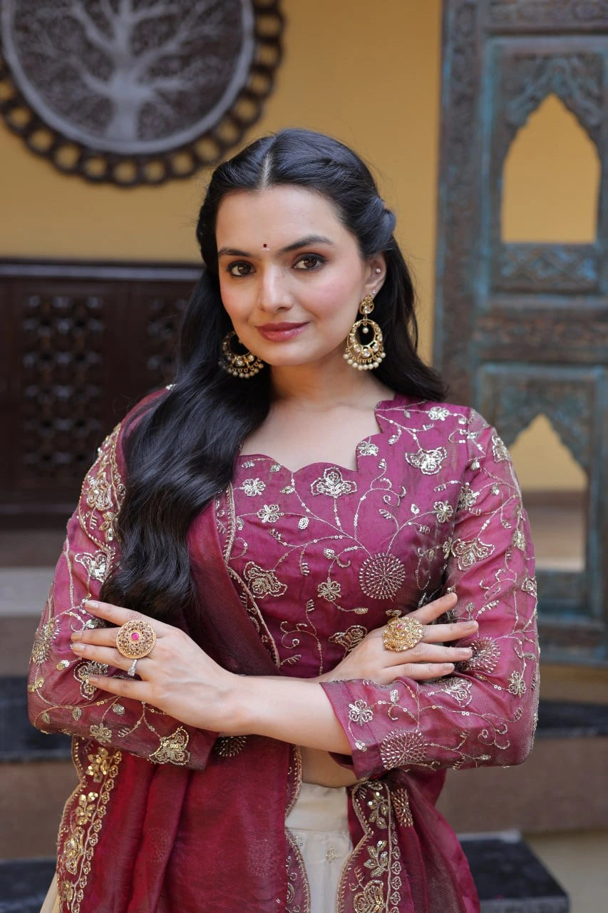 Woman in traditional pink embroidered outfit with gold jewelry in a decorative setting