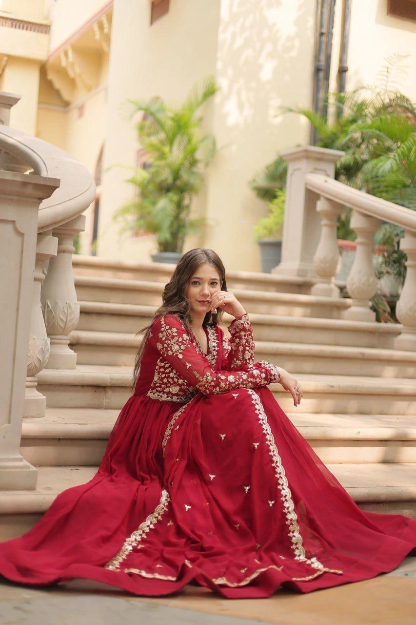 Woman in a red traditional outfit sitting on stone steps with decorative elements.