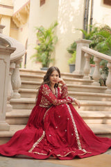 Woman in a red traditional outfit sitting on stone steps with decorative elements.
