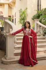 Woman in a red traditional outfit standing on a staircase with decorative elements.