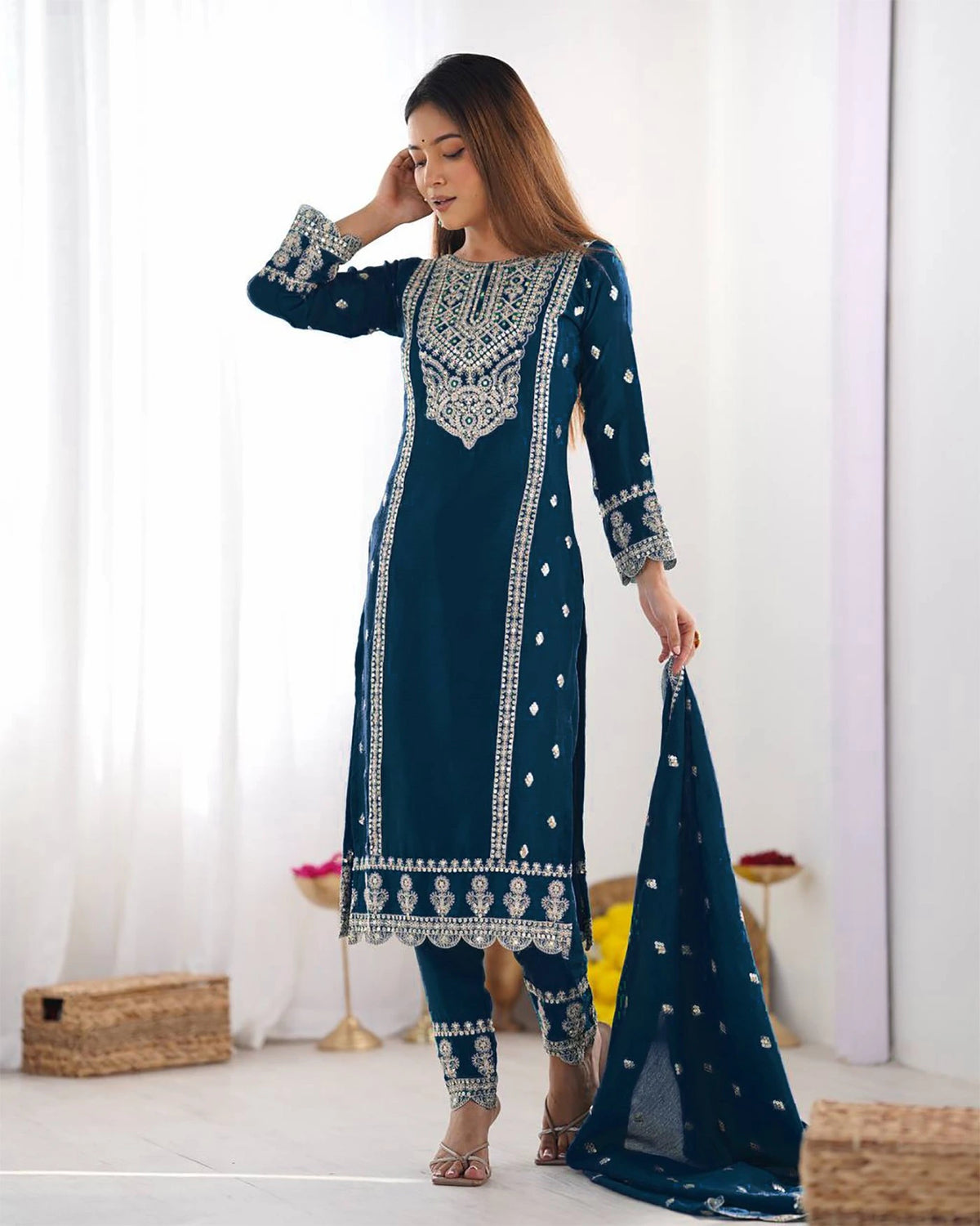 Woman wearing a blue embroidered traditional outfit with a white background