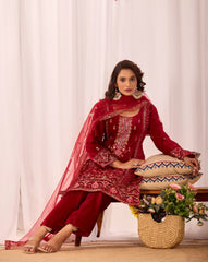 Woman in a red traditional outfit sitting on a stool with a white curtain background