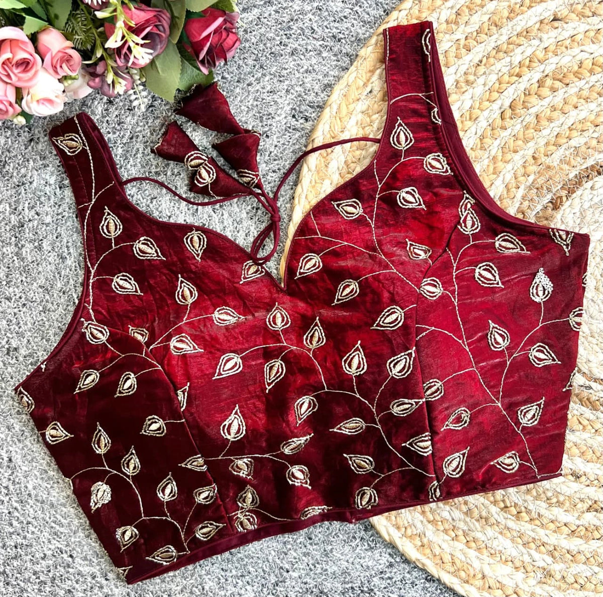 Red embroidered blouse with floral arrangement on a textured surface