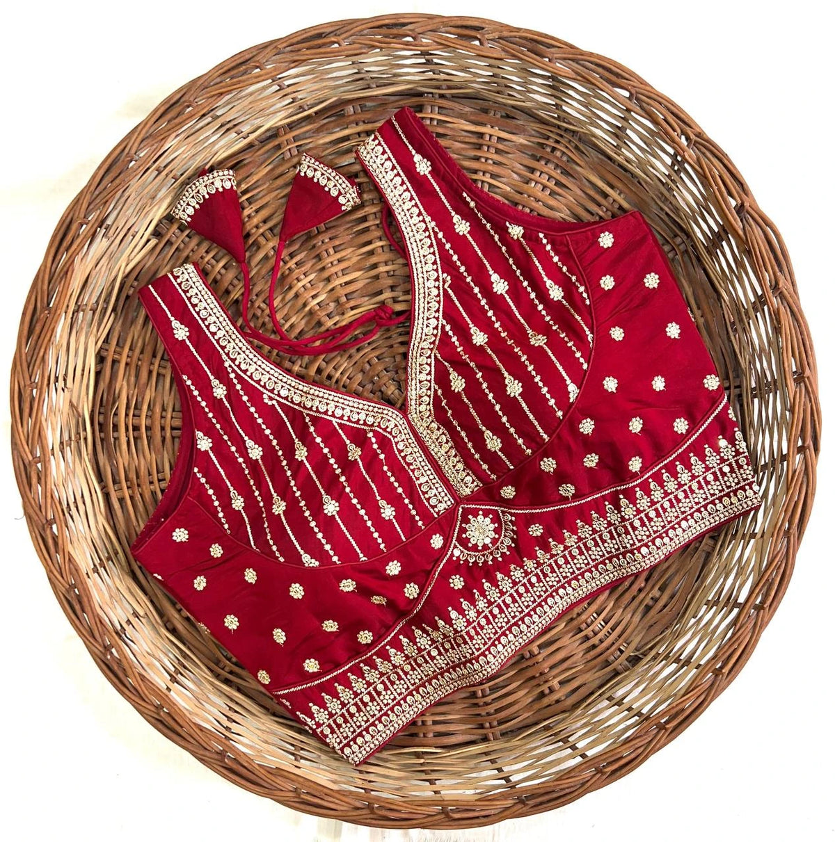 Red embroidered blouse with gold detailing on a woven basket