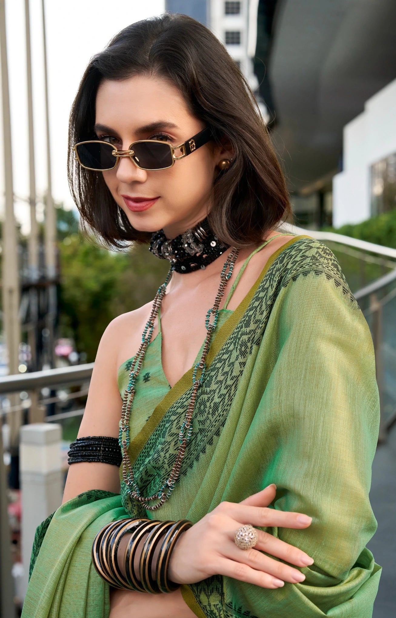 Woman wearing a green saree with jewelry outdoors