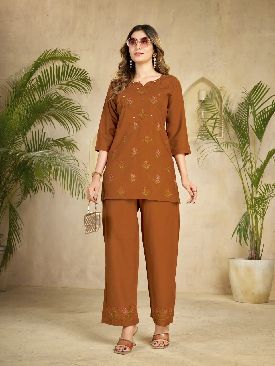Woman wearing a brown traditional outfit with plants in the background