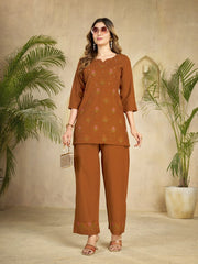 Woman wearing a brown traditional outfit with plants in the background