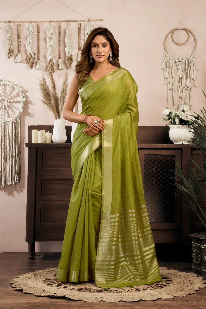 Woman wearing a green saree in a room with decorative elements.