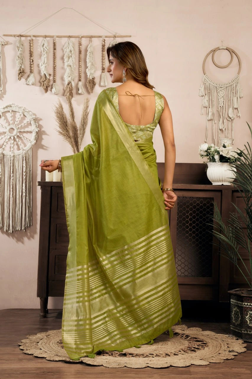 Woman in a green saree standing in a room with decorative elements.