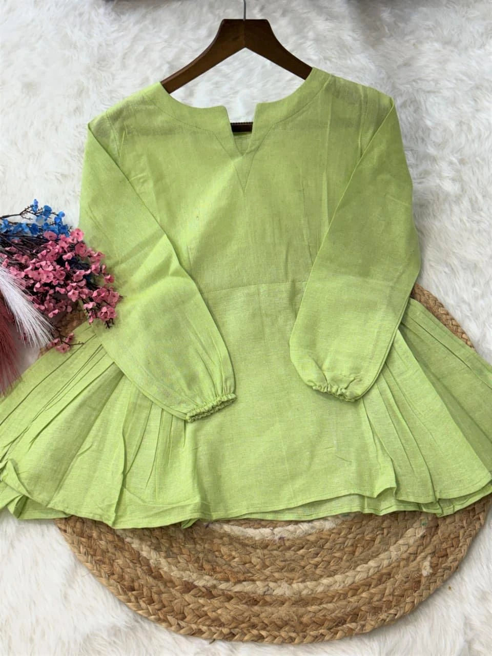 Green dress on a hanger with a textured white background