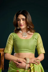 Woman wearing a green traditional outfit with jewelry against a dark background
