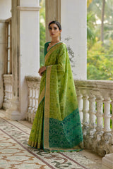 Woman in a green saree standing on a balcony with a garden view