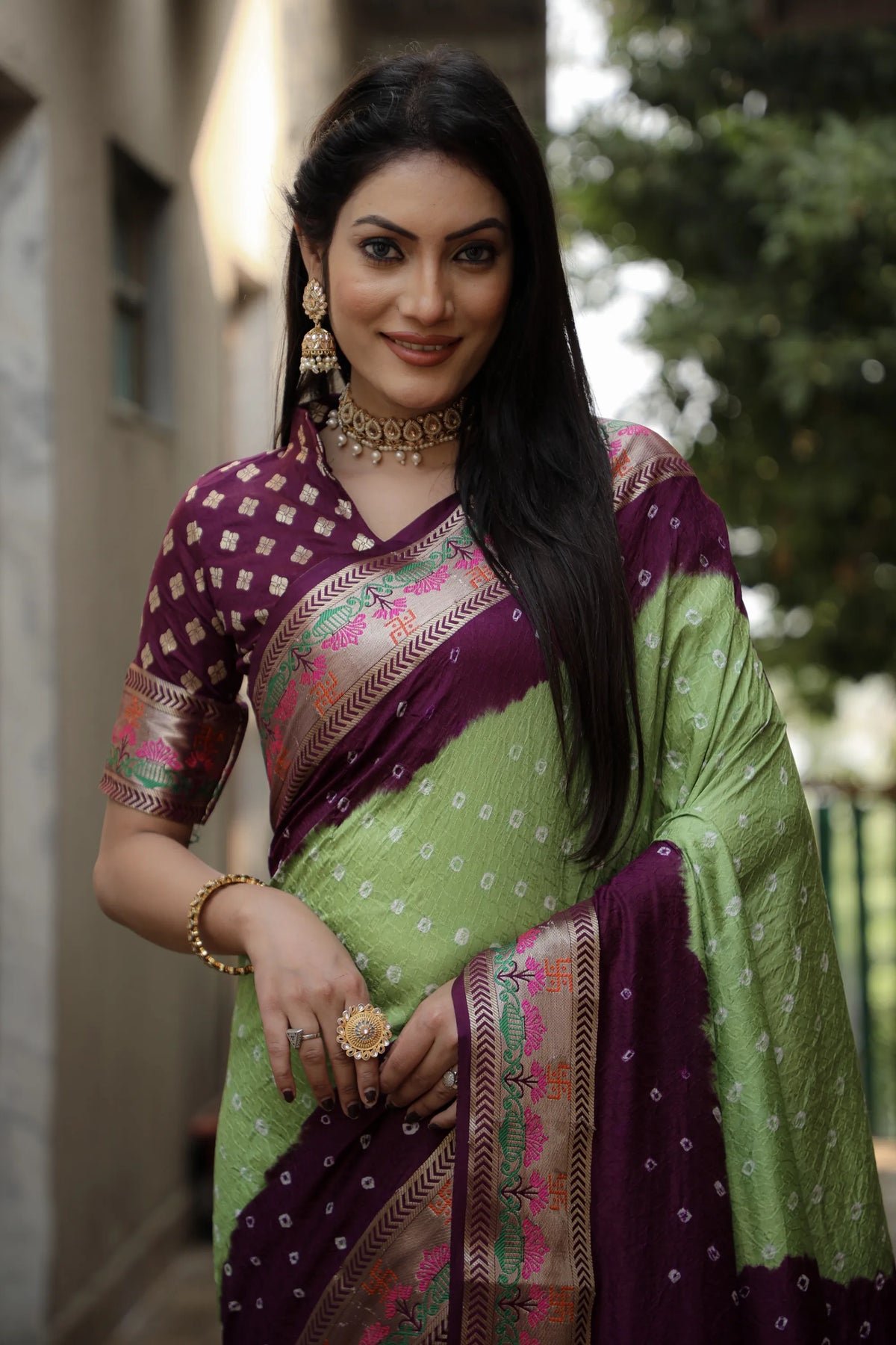 Woman wearing a green and purple saree with a blurred background