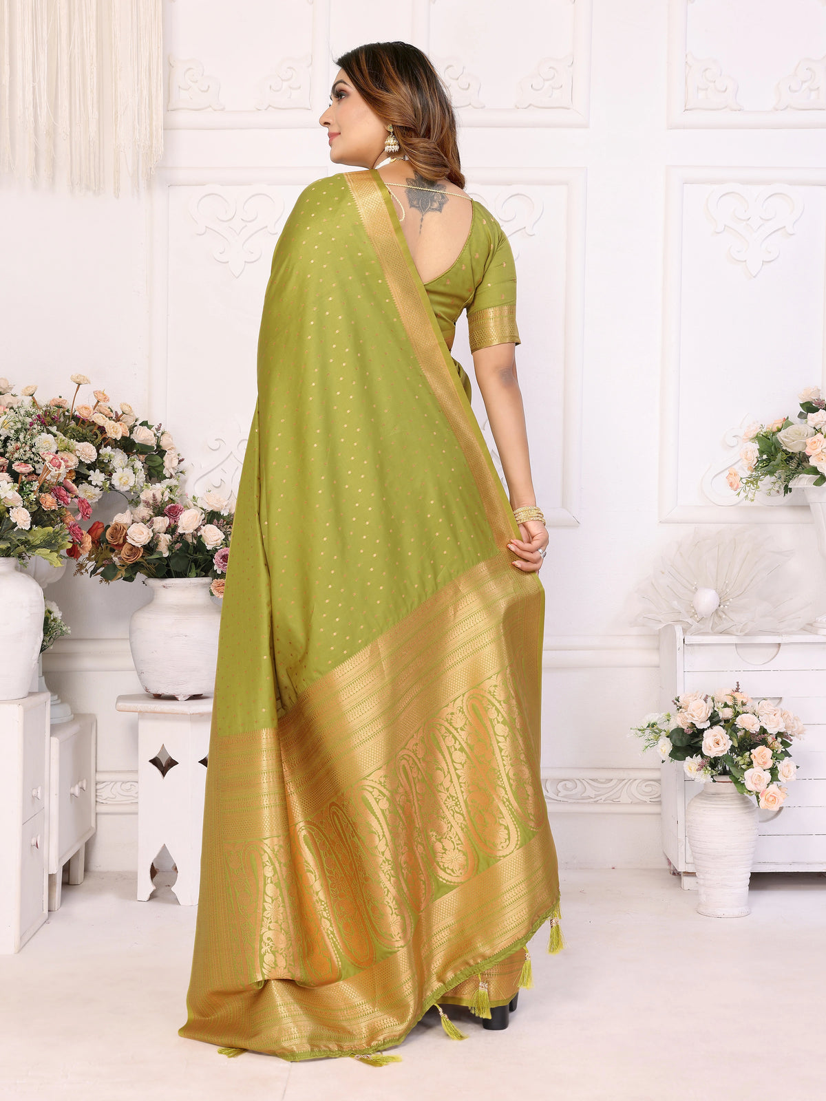 Woman wearing a blue saree with white patterns in a white room.