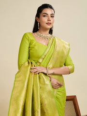 Woman wearing a green saree with a matching blouse against a beige background