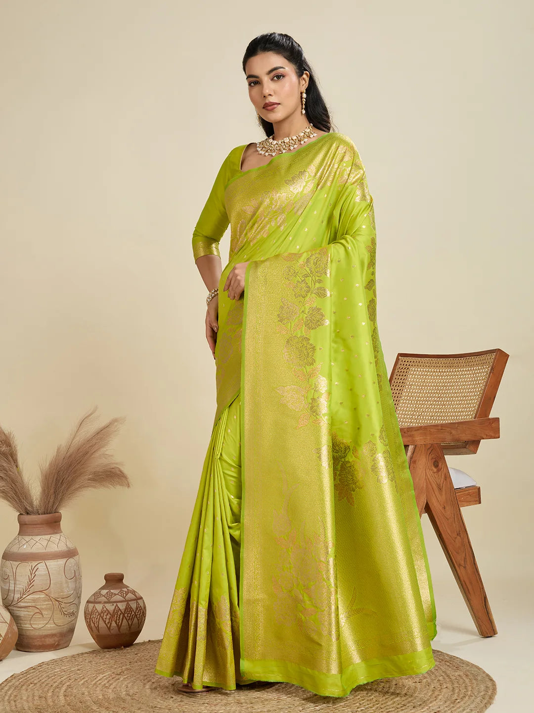 Woman wearing a green saree with a gold border on a beige background