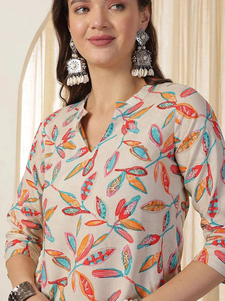 Woman wearing a colorful patterned top with a neutral background