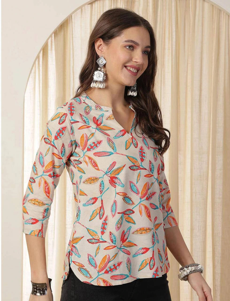 Woman wearing a colorful feather-patterned blouse against a neutral background