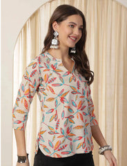 Woman wearing a colorful feather-patterned blouse against a neutral background