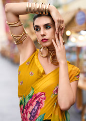 Woman wearing a yellow saree with floral patterns and gold jewelry.