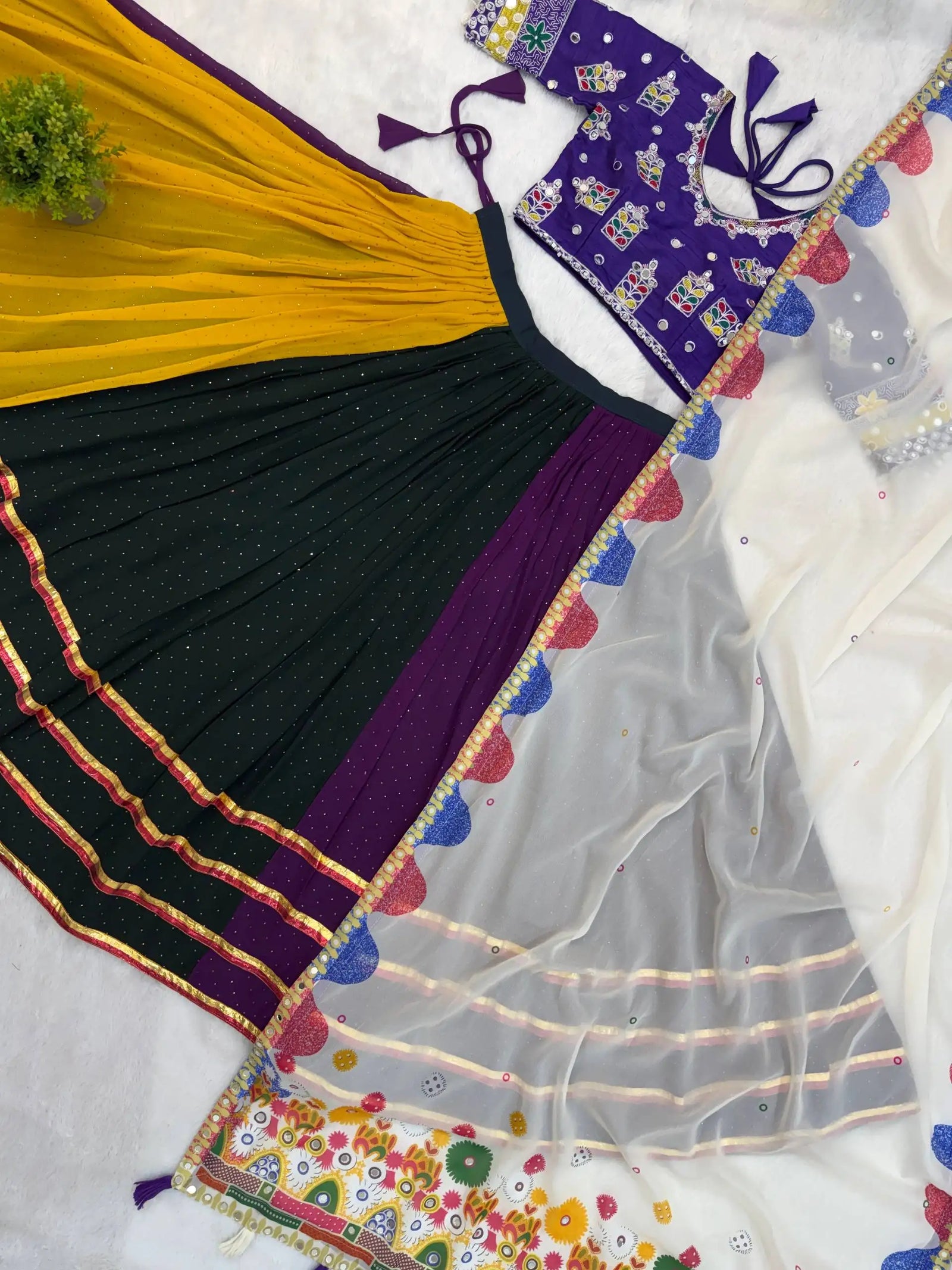 Flat lay detail of lehenga skirt panels showing mustard, green and purple with gota border
