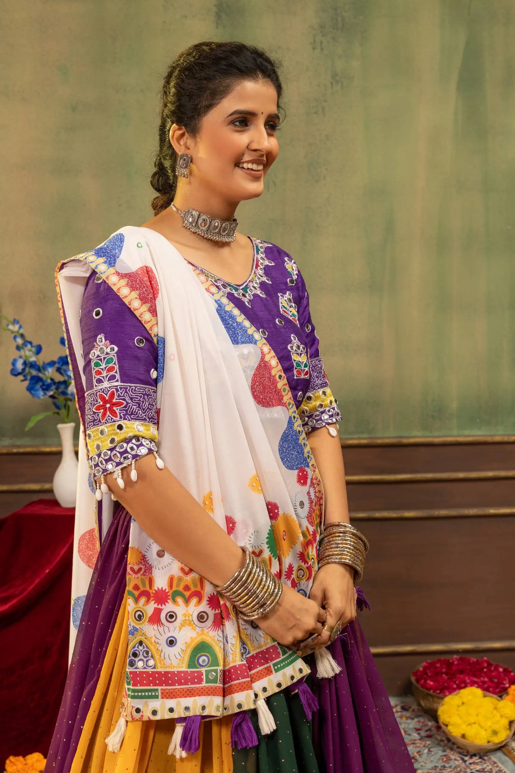 Portrait of model wearing purple Kutchi embroidered choli with mirror work and Kutchi printed dupatta