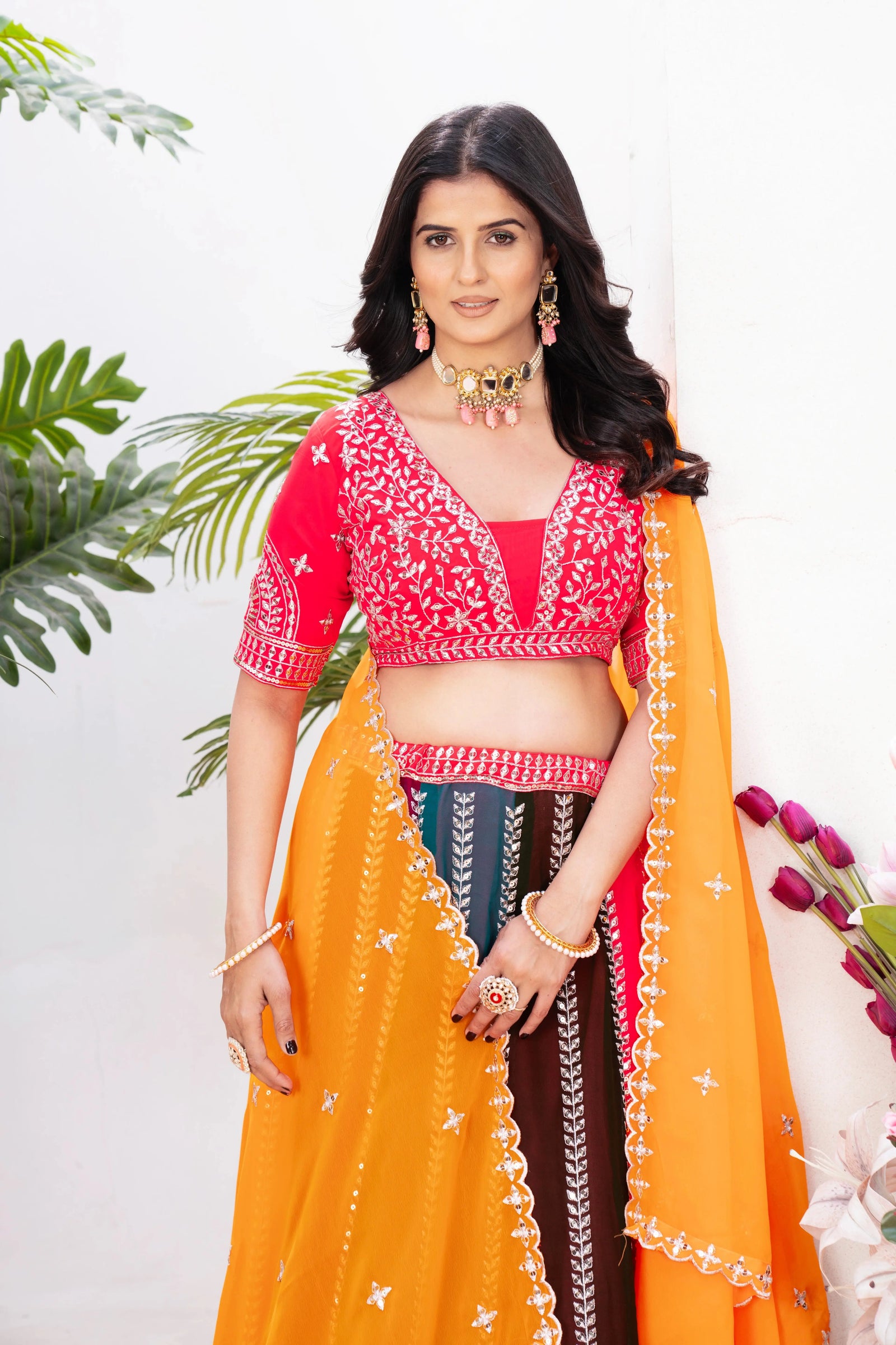 Red embroidered choli with curved neckline, short sleeves and silver zari sequins work close-up