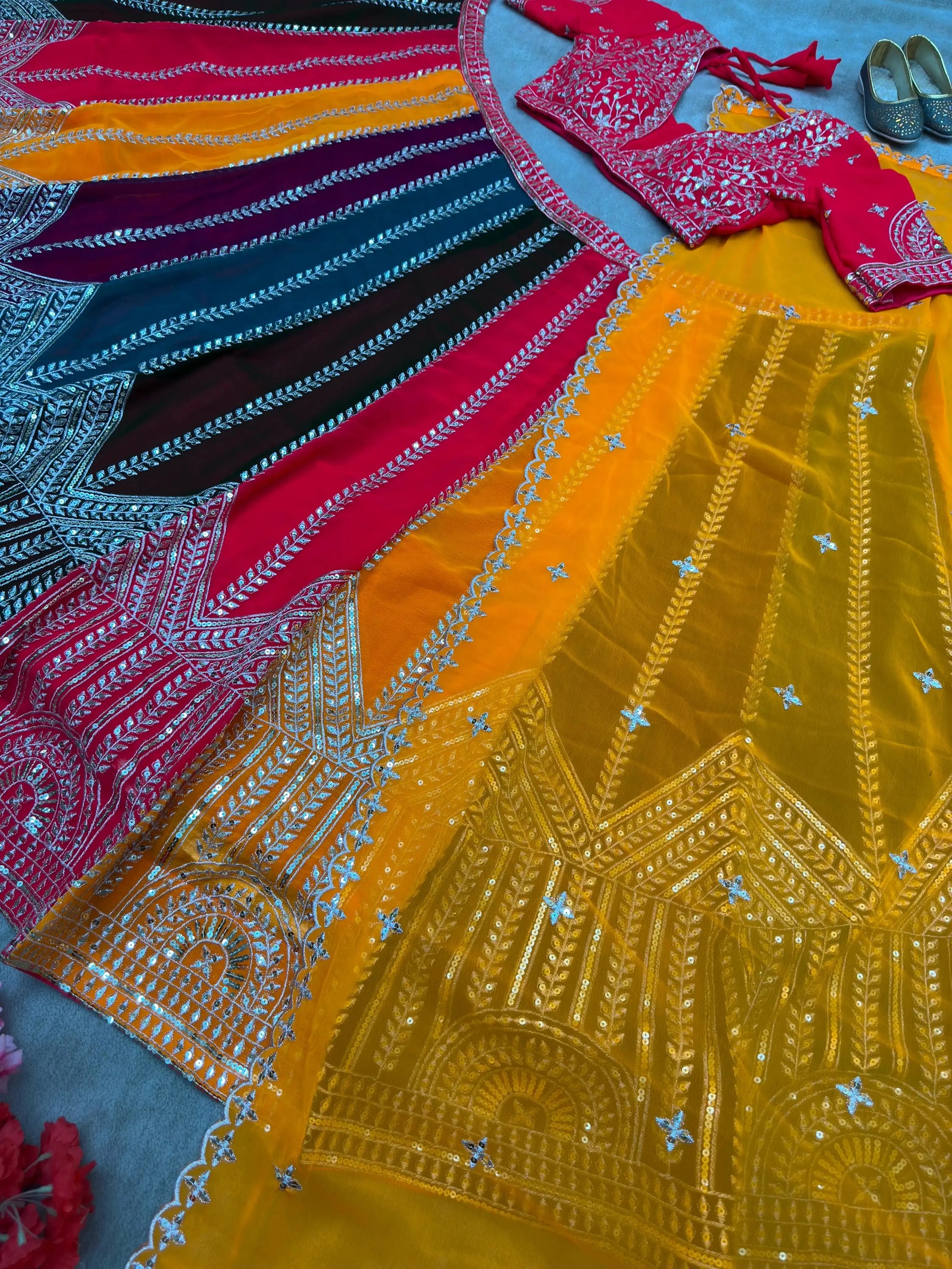 Flat lay of full multicolor lehenga set showing panelled skirt with geometric hem zari embroidery