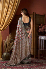Woman in a patterned saree standing in a room with decorative elements.