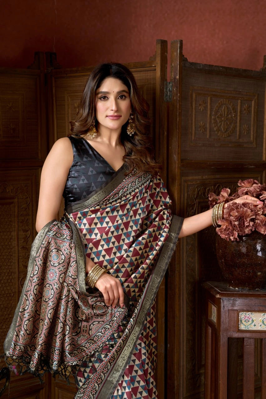 Woman wearing a traditional saree in an indoor setting with wooden furniture and decorative elements.