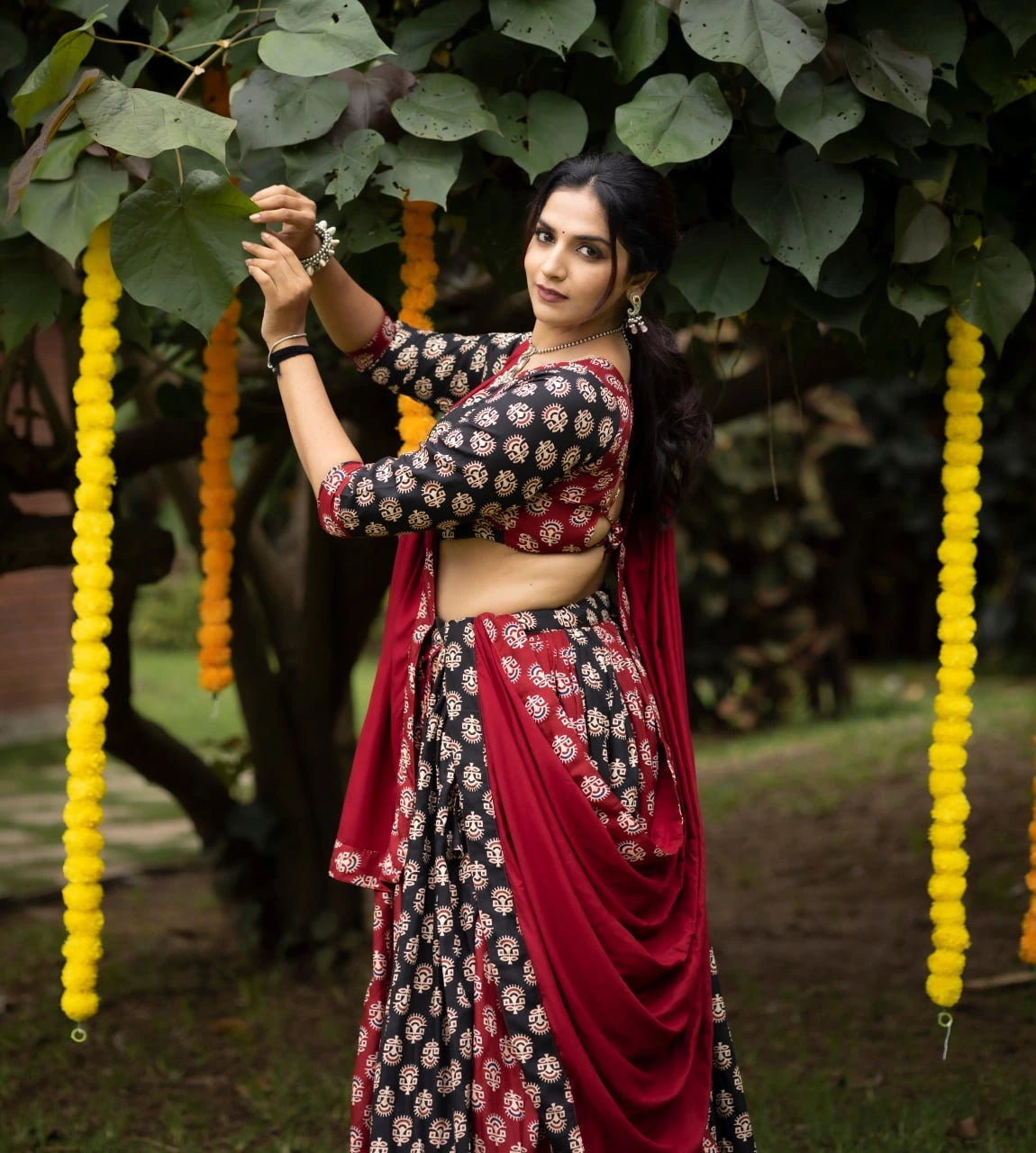 Woman in traditional saree standing outdoors with decorative elements