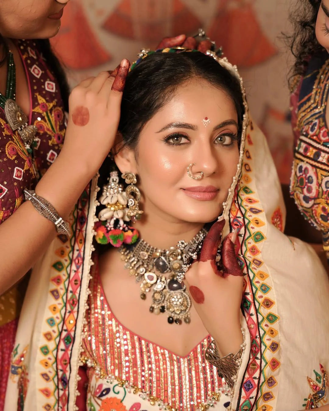 Woman in traditional attire with jewelry and a colorful background