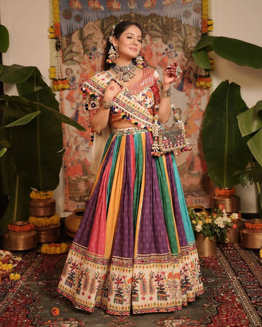Woman in a colorful traditional outfit with intricate patterns, standing in a decorated indoor setting.