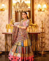 Woman in a colorful traditional outfit standing in an ornate room with chandeliers.