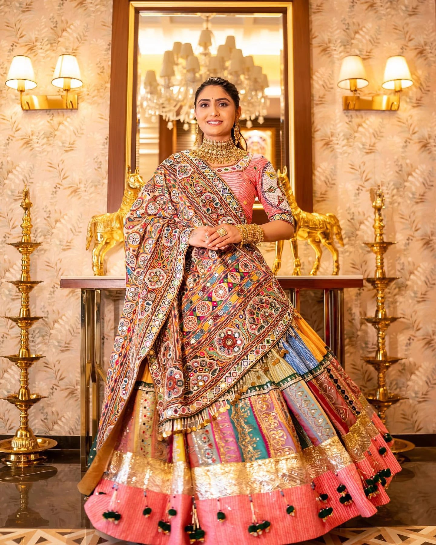 Woman in traditional multicolored outfit with intricate patterns in a decorated room.